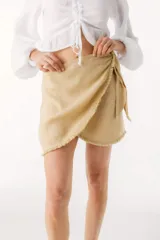 Minifalda color beige de lino, con corte cruzado y lazo lateral.