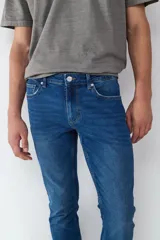Jean de corte slim fit en color azul oscuro, con diseño clásico de cinco bolsillos, cierre frontal con botón y cremallera.