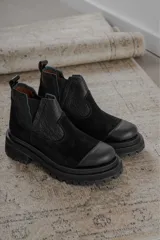 Bota tipo chelsea de punta redonda, confeccionada en una combinación de cuero texturizado y gamuza en tonos marrones. Presenta elásticos laterales negros y una suela track robusta de goma negra.