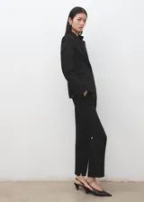 Pantalon de vestir negro de corte recto y tiro medio, con trabillas, bolsillos laterales y bolsillos de ribete en la parte posterior.