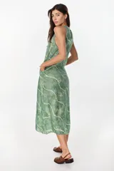 Vestido midi verde de lino italiano, con diseño sin mangas, cuello redondo y estampado de líneas onduladas punteadas. Cuenta con bolsillos laterales.