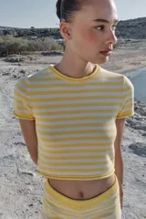 Top corto de punto con diseño a rayas horizontales en color amarillo y blanco, cuello redondo y manga corta.