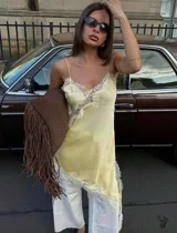 Vestido corto de satén color amarillo pastel con diseño asimétrico. Presenta detalles de encaje blanco en el escote, lateral y ruedo, con breteles finos ajustables.