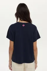 Remera de algodón azul marino de manga corta, con estampa frontal de flores grandes en tonos rosados y motivos geométricos, y detalle de bordado.