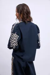 Blusa azul marino con cuello mao, mangas 3/4 abullonadas y bordados en color crema en hombros y mangas.