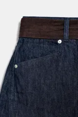 Jeans de mezclilla azul oscuro, tiro medio, corte barrel leg extremadamente ancho y holgado. Incluye un cinturón contrastante de color marrón oscuro con hebilla metálica redonda.