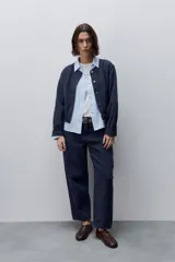 Campera azul marino de algodón, de corte relajado y largo corto, con cuello redondo, cierre frontal con botones metálicos, bolsillos delanteros y mangas largas con puños ajustables.