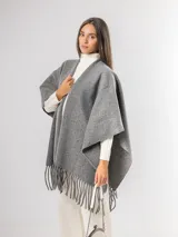 Ruana gris de tejido de punto con flecos en el ruedo.