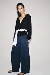 Pantalón de tiro medio con pierna ancha, confeccionado en mezcla de lyocell y viscosa. Cuenta con cintura elástica ajustable con cordones y bolsillos laterales ocultos en la costura.