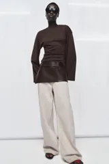 Cinturón tipo falda confeccionado en piel 100% color marrón oscuro, con diseño envolvente y cierre mediante lazada frontal.