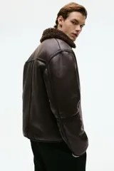 Campera de tejido revestido con acabado efecto cuero envejecido, cuello de solapa con forro de sherpa, cierre frontal y bolsillos laterales con cierre.