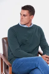 Buzo de punto color verde oscuro, con cuello redondo y mangas largas.