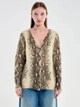 Cardigan de punto con escote en V y cierre frontal de botones. Presenta un diseño de animal print tipo serpiente en tonos beige, marrón y gris, con un calce relajado y textura suave.
