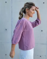 Blusa de mangas tres cuartos con diseño de corte recto y cuello redondo. Presenta costuras horizontales decorativas en las mangas y un acabado liso.