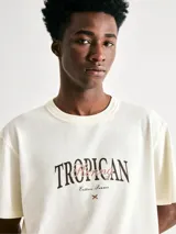 Remera beige de manga corta con estampa frontal con la palabra 'Tropican' en letras negras y detalles en color bordó.