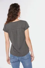 Remera color beige con cuello redondo, mangas cortas, bolsillo pequeño en el pecho y media botonadura frontal.