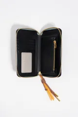 Billetera rígida de color negro con cierre de cremallera perimetral. Presenta el logo metálico de Bimba y Lola en color dorado en el frente y un tirador de cordón trenzado en tonos marrón y amarillo. El interior cuenta con compartimentos para tarjetas y un monedero con cierre.