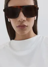 Camiseta sin mangas de color blanco, de diseño recto, con cuello redondo y hombreras, con corte peplum en la parte inferior.