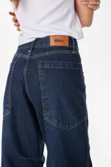 Pantalón jean de corte amplio y relajado, color azul oscuro, con bolsillos traseros grandes y detalles de costuras marcadas.