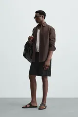 Bermuda de lino color blanco hueso, de corte relajado y tiro medio. Presenta cintura elástica ajustable con cordón, pliegues frontales y bolsillos laterales y trasero.