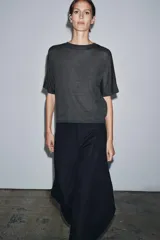 Jersey de punto liso color gris oscuro, con cuello redondo y mangas cortas amplias.