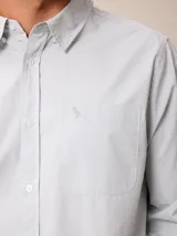 Camisa de manga larga en color blanco, confeccionada en algodón. Presenta cuello abotonado, cierre frontal con botones y un bolsillo en el pecho.