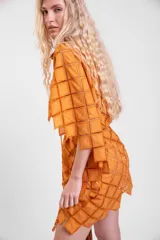 Vestido camisero oversize de color naranja en tela calada con diseño geométrico, cuello tipo solapa, mangas anchas y ruedo con terminación en picos. Cuenta con lazo ajustable en la cintura.