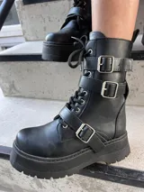 Bota de caña media confeccionada en cuero sintético de alta calidad, con diseño de estilo militar que incorpora cintas decorativas con hebillas metálicas, plataforma y taco cuadrado.