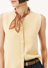 Chaleco de punto sin mangas en color amarillo suave, con cuello en V y cierre frontal de botones al tono. Presenta un diseño clásico y minimalista con un pequeño bordado decorativo en la parte inferior.