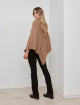 Poncho tejido color crema, con cuello polera y diseño trenzado diagonal en el frente. Presenta un corte asimétrico en el ruedo.