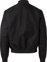 Campera bomber negra Calvin Klein de satén de nailon reciclado, con cuello, puños y bajo de punto de canalé. Tiene cierre de cremallera, bolsillos de hendidura en la cintura, detalle de cremallera en la manga e insignia con el logo de goma de Calvin Klein en la manga. El forro y el relleno son de poliéster reciclado REPREVE®.