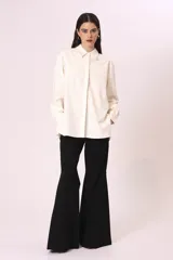 Camisa blanca de corte oversize, con cuello clásico y mangas largas con puños abotonados.