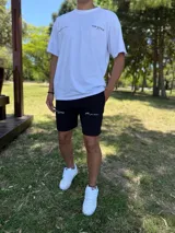 Remera blanca oversize con estampado tipográfico negro en la espalda que incluye texto y un gráfico de un globo terráqueo.