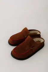 Zueco de cuero color marrón oscuro, con costuras decorativas en hilo rojo en el empeine y suela plana de goma.