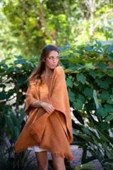 Ruana tejida color ocre con flecos en el borde inferior.