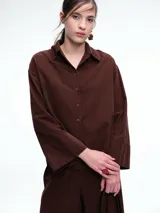 Camisa oversize de lyocell color tostado, con cuello clásico, cierre frontal de botones y mangas largas con puños anchos. Presenta un diseño de corte relajado con caída fluida.