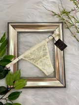 Tanga color champagne de encaje con elástico ancho regulable y entrepierna de algodón.