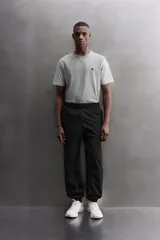 Pantalón jogger negro de corte regular, confeccionado en tejido técnico con algodón. Presenta cintura elástica ajustable con cordón interior, bolsillos laterales y puños elásticos en los tobillos. Posee un pequeño logo estampado en contraste en la pierna derecha.