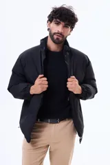 Campera puffer negra de corte estándar, con cuello alto, cierre frontal completo y puños elásticos.