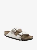 Sandalia Birkenstock modelo Arizona de dos tiras, color blanco nacarado brillante. Presenta hebillas ajustables de metal color cobre y plantilla anatómica de corcho-látex forrada en ante.
