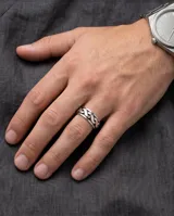 Anillo de plata 925 con diseño empavonado y banda central giratoria con patrón de eslabones entrelazados.