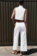 Pantalón blanco de jean con bordados calados en los laterales, de tiro medio y pierna ancha.