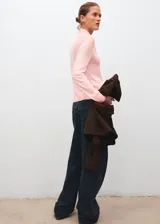 Jersey de punto fino color rosado, con cuello alto y cierre de nudo ajustable, de diseño recto y manga larga.
