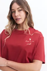 Remera corta (cropped) de algodón color verde lima, con cuello redondo y manga corta. Presenta un pequeño estampado en el pecho con un corazón naranja y texto manuscrito.