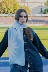Bufanda de tejido de punto en color celeste con diseño de sol blanco estampado en los extremos.