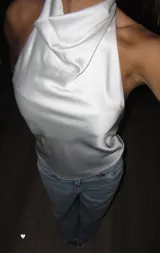 Top de satén color blanco con cuello halter y espalda descubierta. Presenta una caída fluida y un diseño minimalista sin mangas.