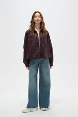 Chaqueta de eco-cuero color marrón oscuro, con cuello camisero, cierre frontal con botones, mangas largas abullonadas con puños y detalles de frunces en los hombros.