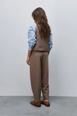 Pantalón marrón de tiro alto y silueta amplia, confeccionado con pinzas en el frente y bolsillos laterales.
