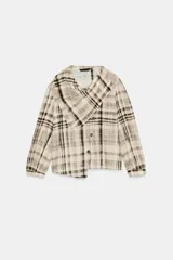 Camisa de manga larga con estampado de cuadros en tonos neutros. Presenta un diseño con cuello tipo pañuelo, cierre frontal cruzado con botones y un corte asimétrico en el ruedo.