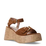 Sandalias de plataforma tipo cuña con acabado símil corcho, color marrón, con tiras de material textil gamuzado, hebillas doradas ajustables en el empeine y pulsera al tobillo.
